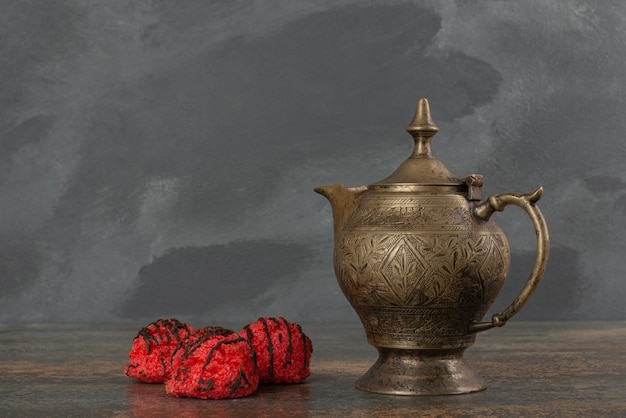 Trois bonbons avec bouilloire ancienne sur table en marbre.