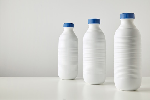 Photo gratuite trois bouteilles en plastique blanc vierge à rayures avec des bouchons bleus en ligne isolé sur table