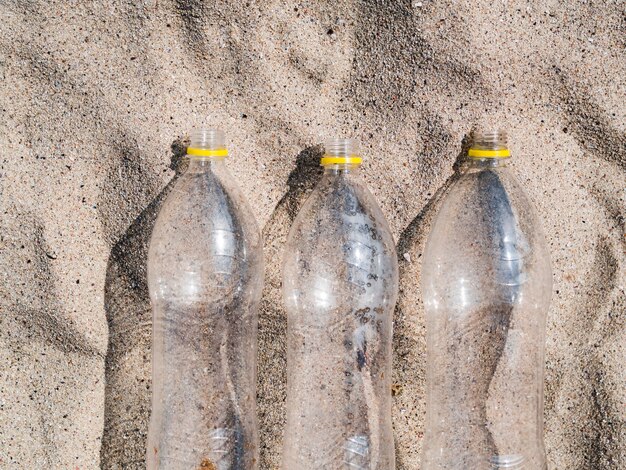 Trois bouteilles en plastique vides organiser dans une rangée sur le sable