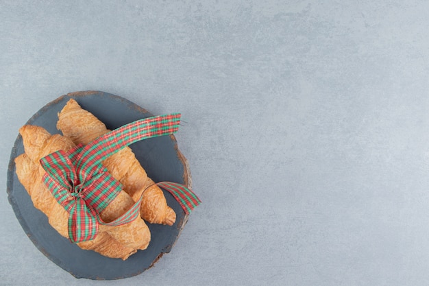 Trois croissants empilés sur le tableau bleu sur le fond de marbre. Photo de haute qualité