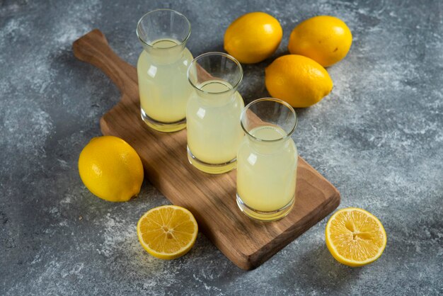 Trois cruches en verre de limonade froide sur planche de bois