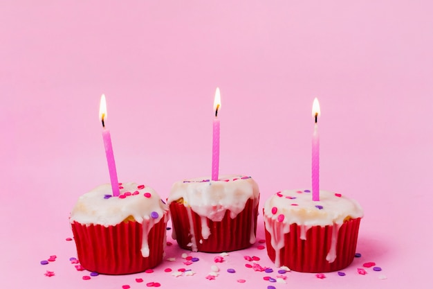 Photo gratuite trois cupcakes avec des bougies allumées