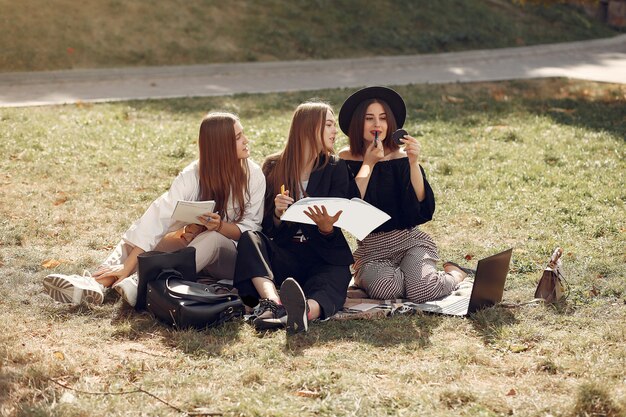 Trois étudiants assis sur l'herbe avec ordinateur portable