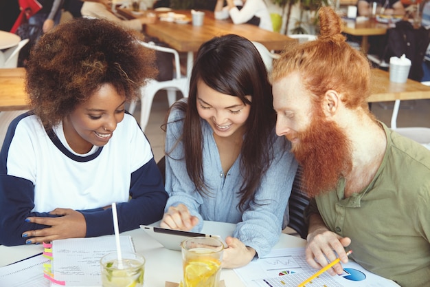 Trois étudiants Travaillant Ensemble à La Maison, Assis Au Café, Faisant Des Recherches, Naviguant Sur Internet, Utilisant Le Wi-fi Sur Le Pavé Tactile.