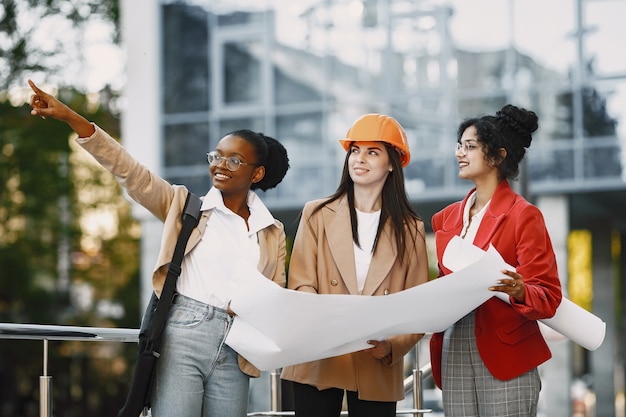 Trois femmes travaillant comme architectes sur une construction et prenant une décision sur le plan d'un bâtiment