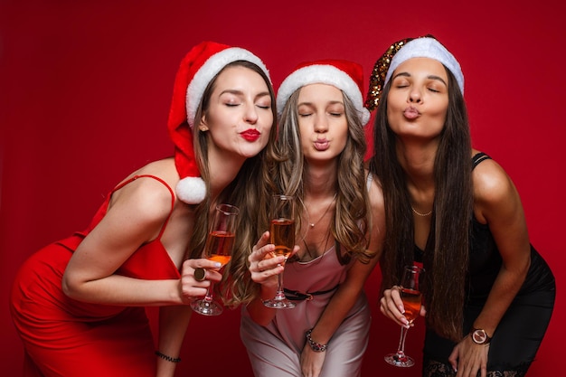 Trois filles avec des boissons faisant des lèvres boudeuses avec les yeux fermés.