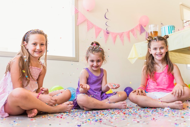 Trois filles mignonnes assis sur le sol en profitant d&#39;une fête