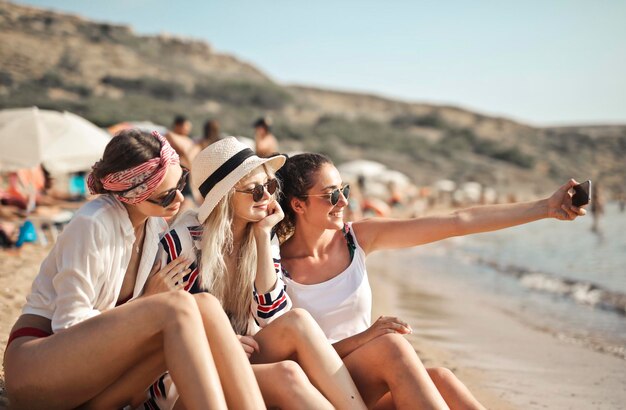 trois filles sur la plage prennent un selfie