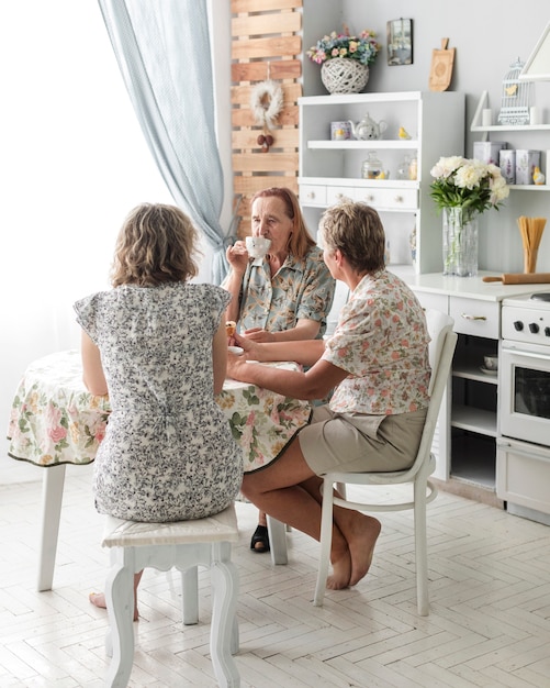 Photo gratuite trois générations de femmes buvant du café ensemble dans la cuisine