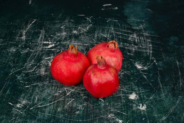 Trois grenades mûres sur table en marbre.