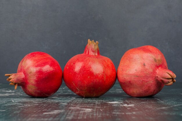 Trois grenades mûres sur table en marbre.