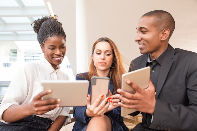 Trois hommes d&#39;affaires heureux à l&#39;aide de gadgets au bureau