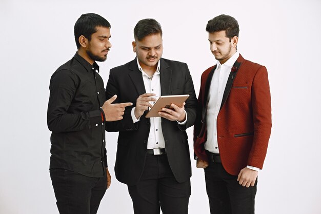 Trois hommes discutant d'idées. Mur blanc. Nationalité indienne.