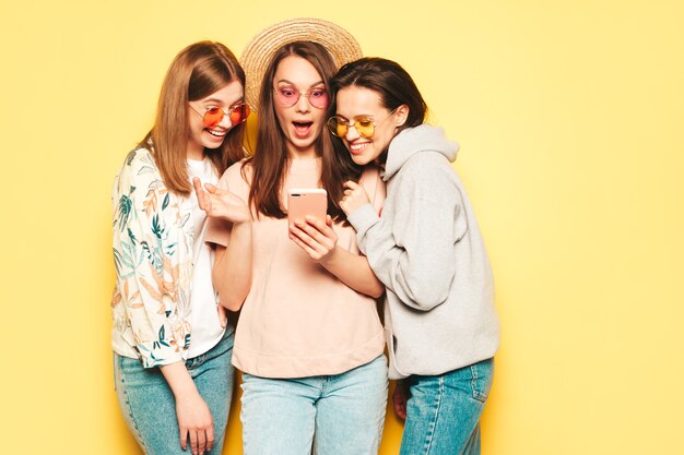 Trois jeunes belles femmes hipster souriantes dans des vêtements d'été à la mode en t-shirt et jeans