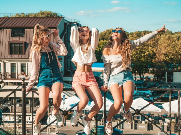 Trois jeunes belles filles hipster souriantes dans des vêtements d'été à la mode