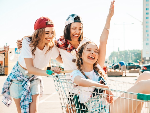 Trois jeunes belles filles s'amusant dans le panier d'épicerie