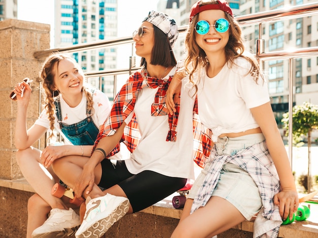 Photo gratuite trois jeunes filles belles souriantes avec des planches à roulettes penny colorées.