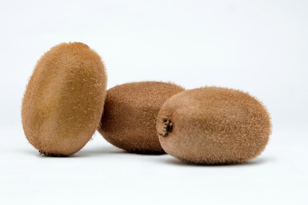 Trois kiwis sur une surface blanche