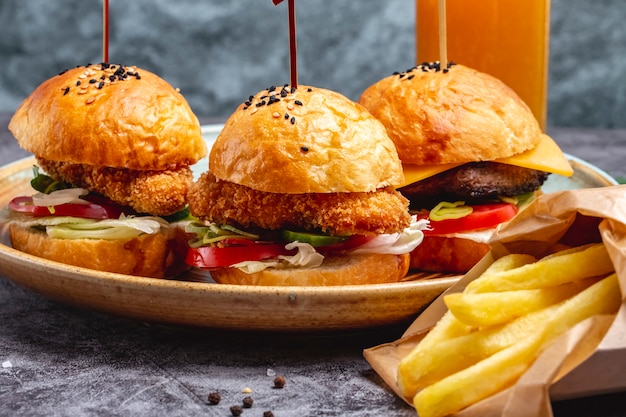 Photo gratuite trois mini hamburgers servis avec des frites dans une boîte en papier