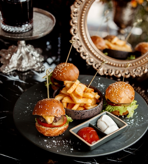 Trois mini hamburgers servis avec frites, tomate et mayonnaise