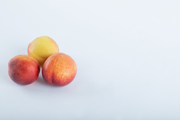 Photo gratuite trois nectarines fraîches sur blanc.