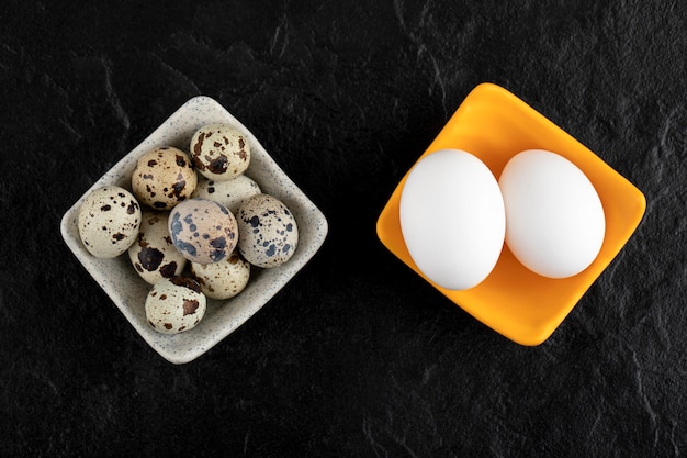 Trois œufs de caille et œufs de poule sur une surface noire