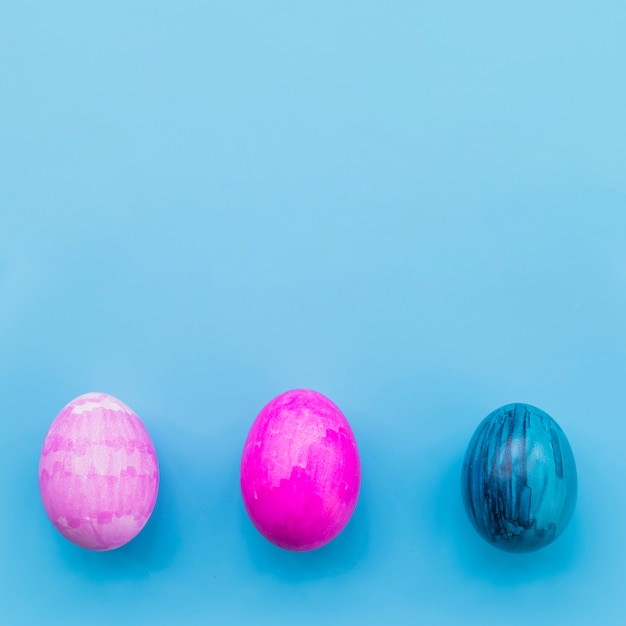 Trois oeufs colorés sur fond bleu