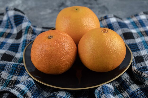 Trois oranges mûres sur plaque noire.