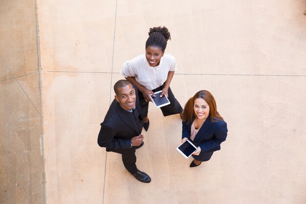 Trois personnes heureuses avec tablette posant