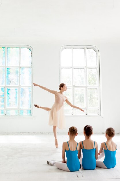 Trois petites ballerines dansant avec un professeur de ballet personnel en studio de danse
