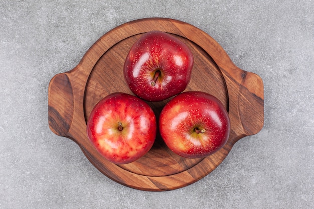 Trois pommes rouges sur planche de bois