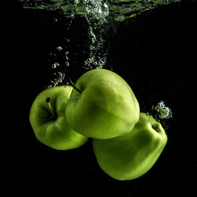 Photo gratuite trois pommes vertes fraîches dans l'eau