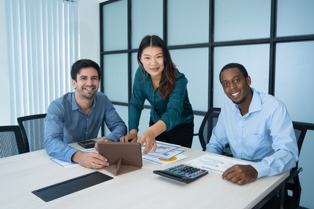 Trois professionnels souriants ont discuté des nouveaux projets à la table de conférence.