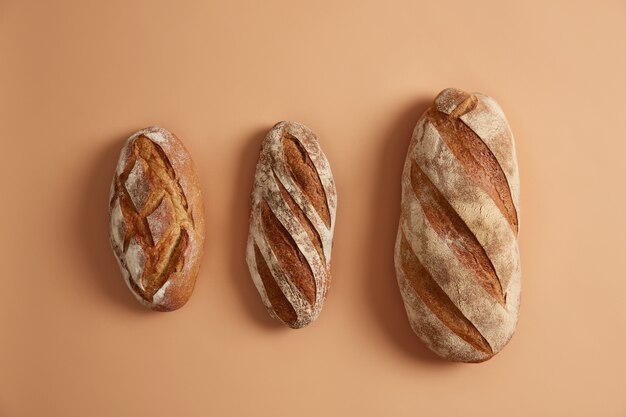 Trois savoureuses miches de pain disposées sur fond beige. Produits de boulangerie faits maison sans gluten. Pain blanc bio au sarrasin fraîchement sorti du four sur levain. Concept de cuisson innovant. Tir aérien