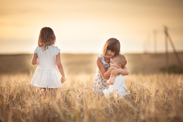 Trois sœurs filles marchent dans le champ avec le coucher du soleil de seigle