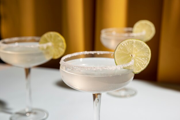 Trois sous-verres de cocktail margarita garnir de citron vert sur la table