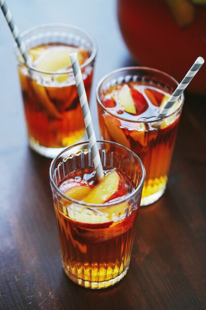 Trois tasses de jus de pêche jaune sur la table en bois