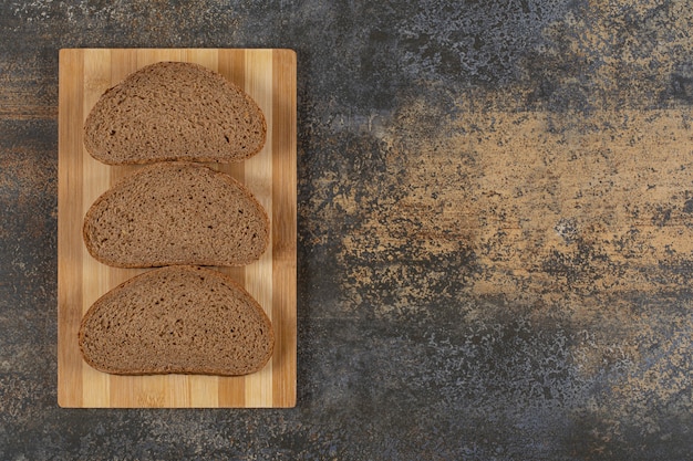 Trois tranches de pain noir sur planche de bois.