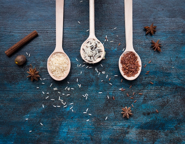 Trois types de riz en cuillères sur table