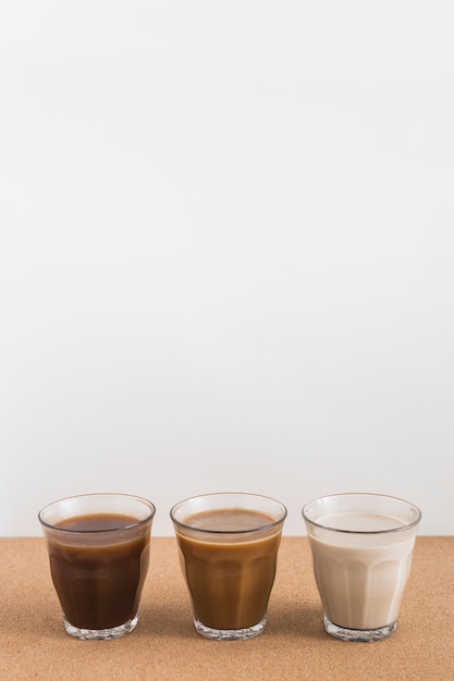 Trois verres affichant différents mélanges de lait et de café sur table