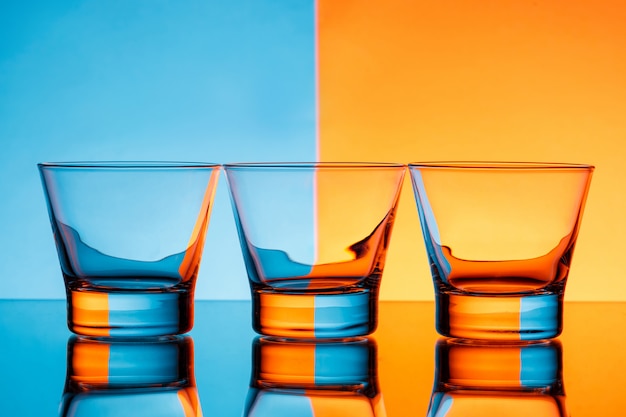 Photo gratuite trois verres d'eau sur fond bleu et orange.