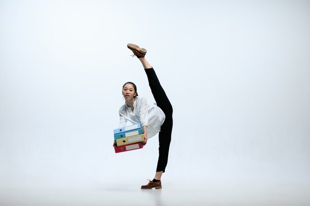 Trop de cas pour la journée. Femme sérieuse travaillant au bureau, sautant et dansant dans des vêtements décontractés ou costume isolé sur fond de studio blanc. Entreprise, start-up, concept d'espace ouvert de travail.