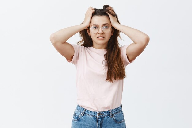 Troublé anxieux jeune brune avec des lunettes posant