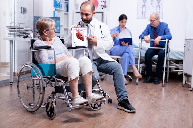 Trucs médicaux présentant un livret d'arythmies à une femme âgée handicapée assise en fauteuil roulant