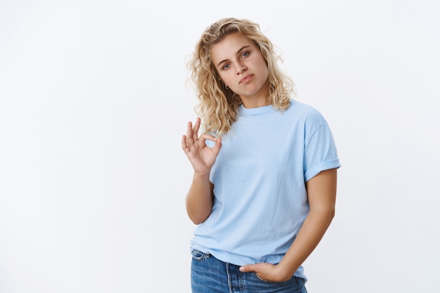 Tu es bon, pas mal du tout. Portrait d'une jeune fille swag cool impressionnée et fière avec de courts cheveux blonds bouclés et des lèvres pincées comme montrant un geste d'approbation et comme un geste