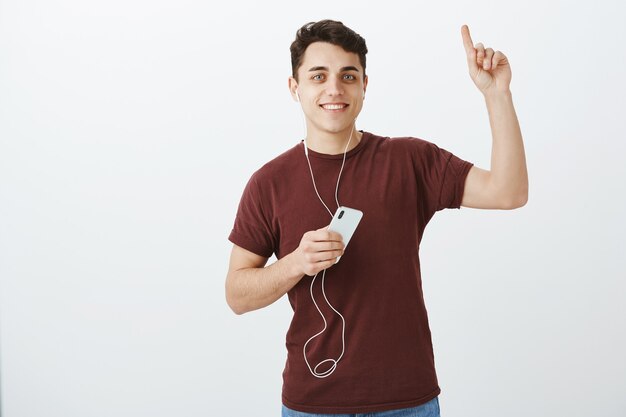 Tu ferais mieux de lever la tête. Portrait de client masculin attrayant positif dans les écouteurs