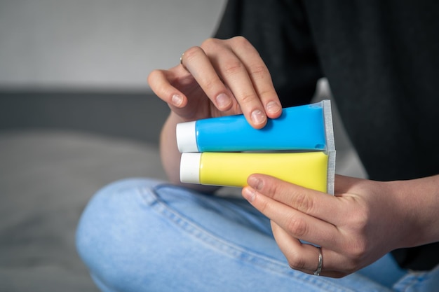 Tubes de peinture jaune et bleue dans les mains des femmes le drapeau de l'ukraine