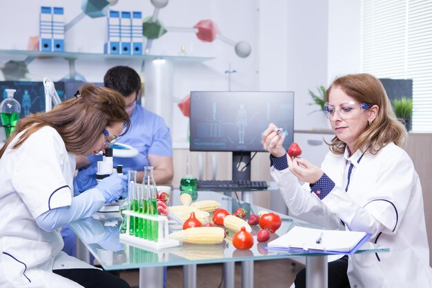 Étude de traitement sur des fraises génétiquement modifiées en laboratoire par un groupe de scientifiques. Tubes à essai avec des solutions vertes.