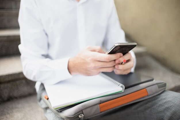 Étudiant à l'aide de son téléphone et assis dans les escaliers