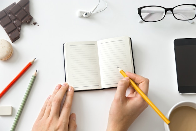 Étudiant, mains féminines, tenant un crayon et un cahier ouvert